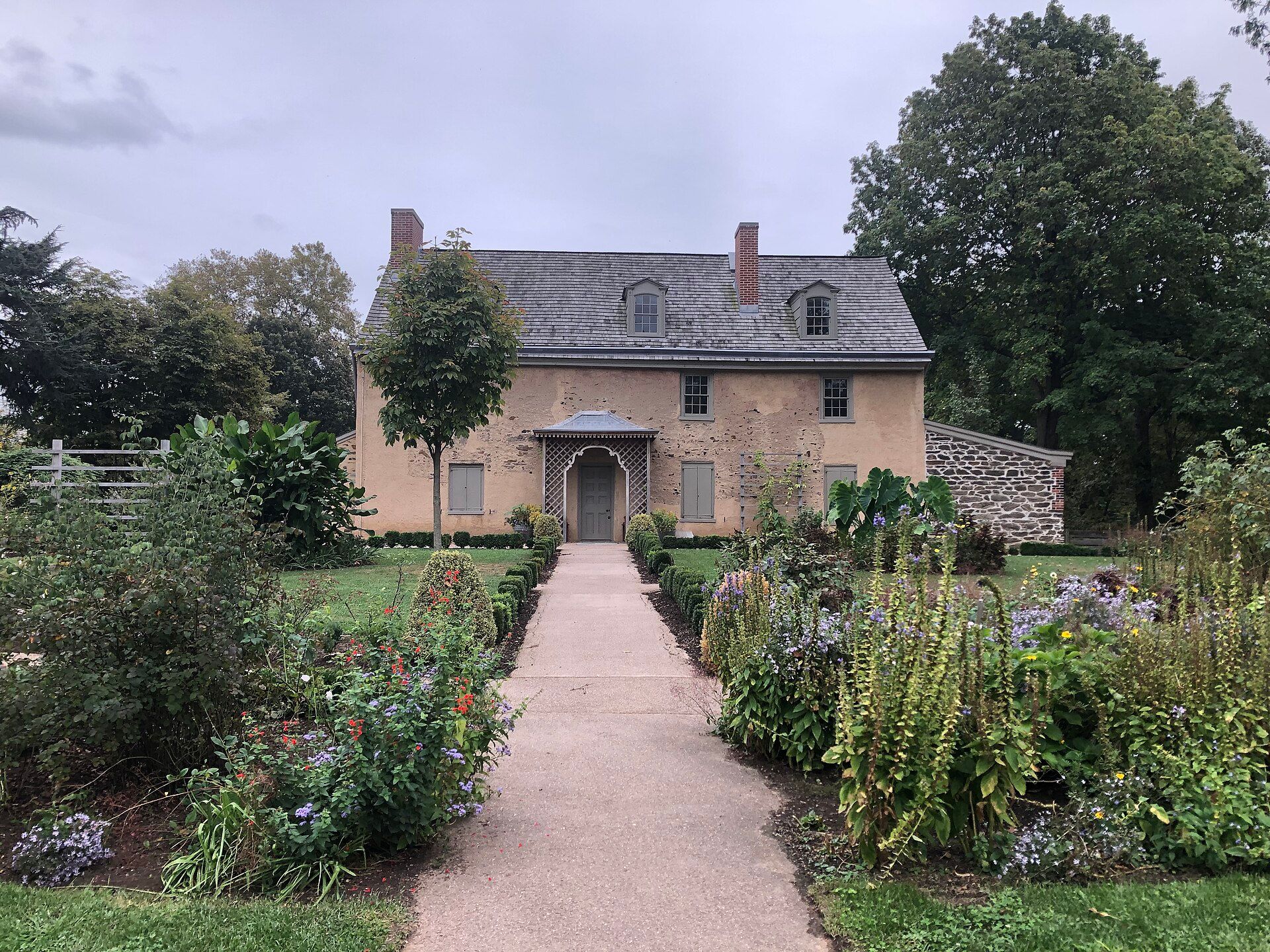 The stone front of John Bartram’s 18th century house behind a path lined with flower beds