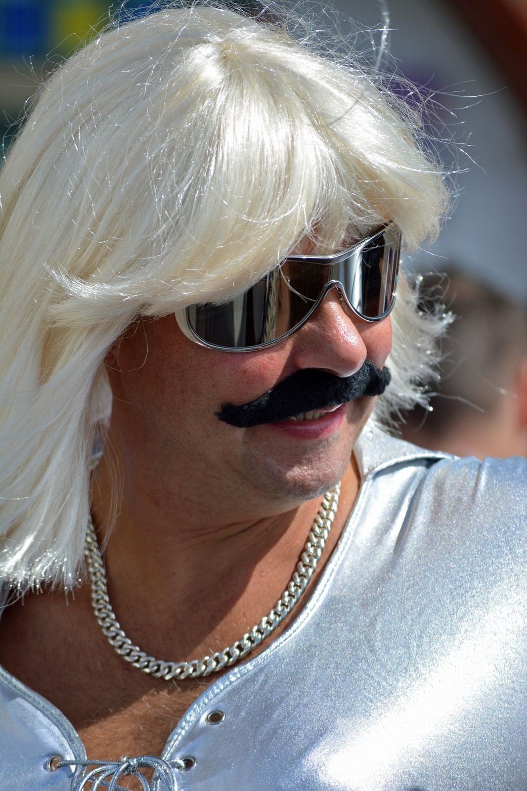 A performer in an elaborate costume and moustache at a pride parade