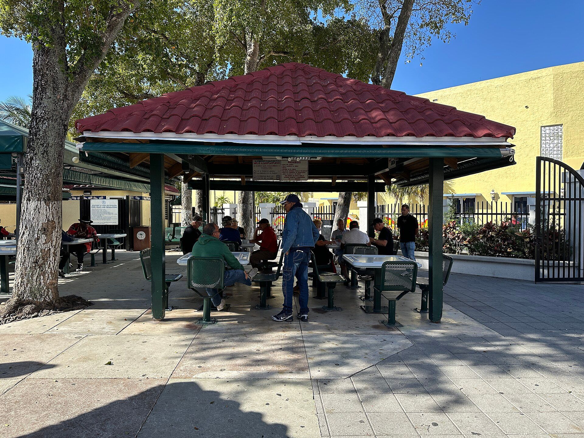 Men playing dominoes under a tiled pavilion at Domino Park on Calle Ocho