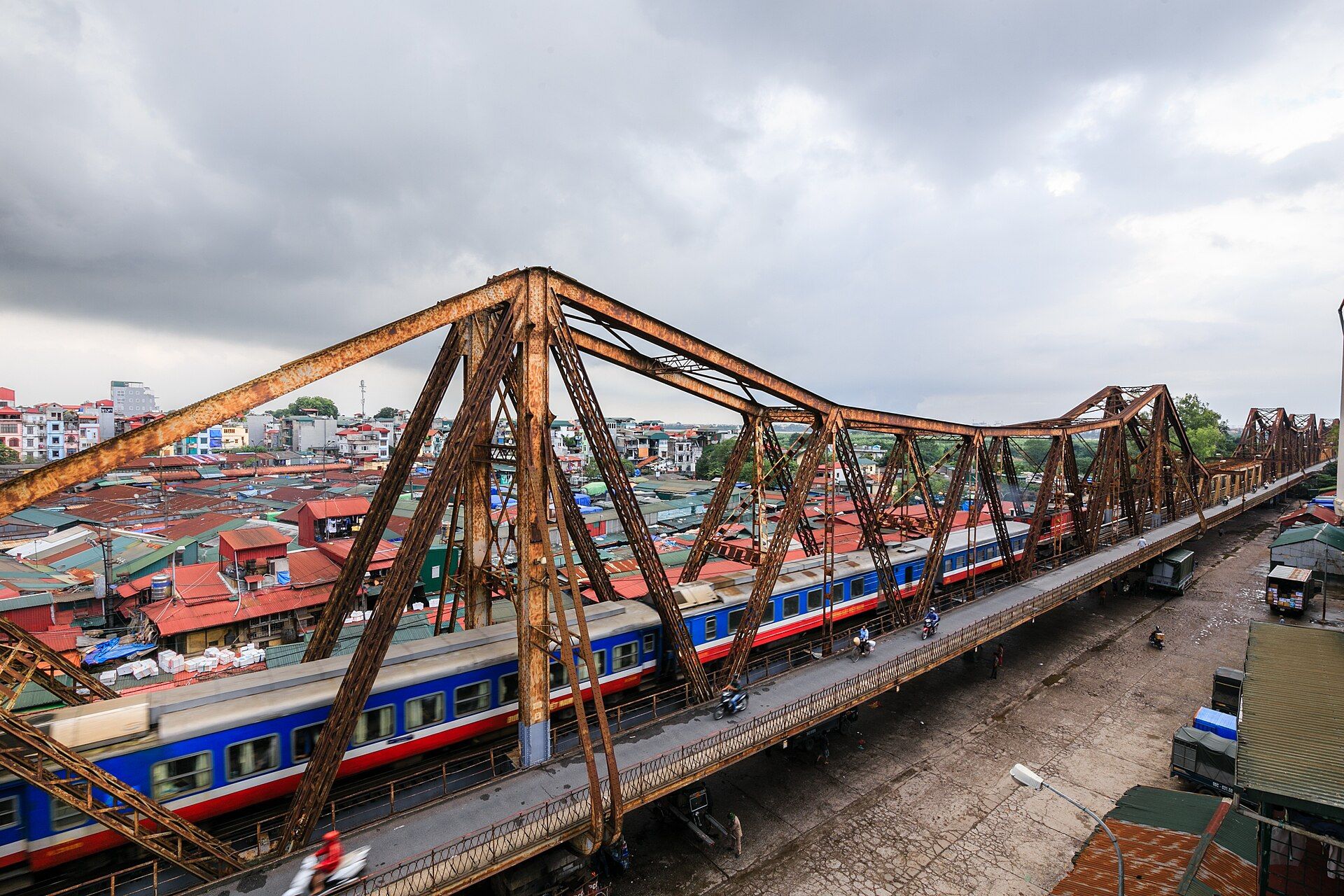 The rusty iron trusses of Long Biên bridge with a train crossing