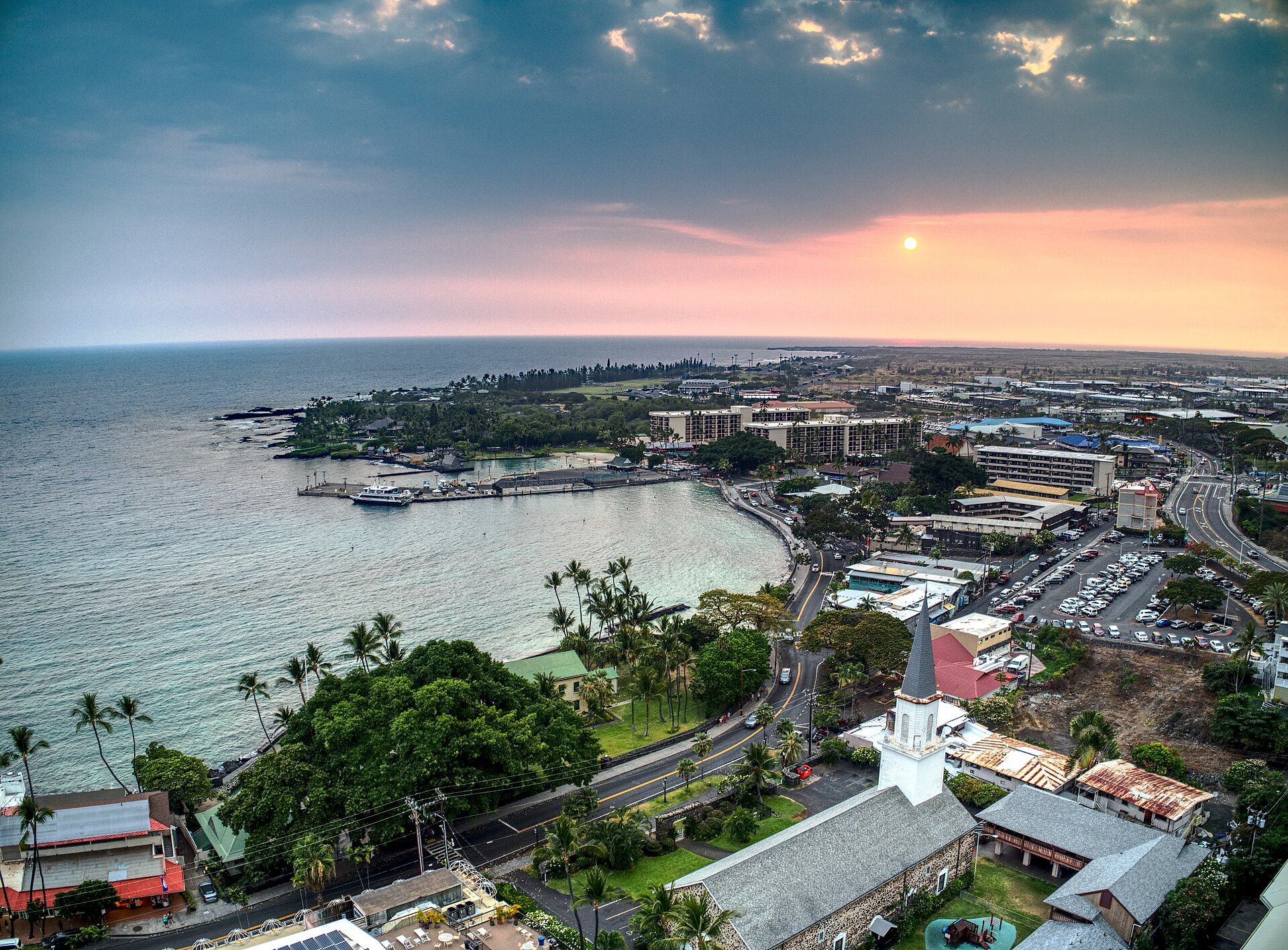Kailua-Kona from the air at sunset, the white church steeple beside the curve of the bay