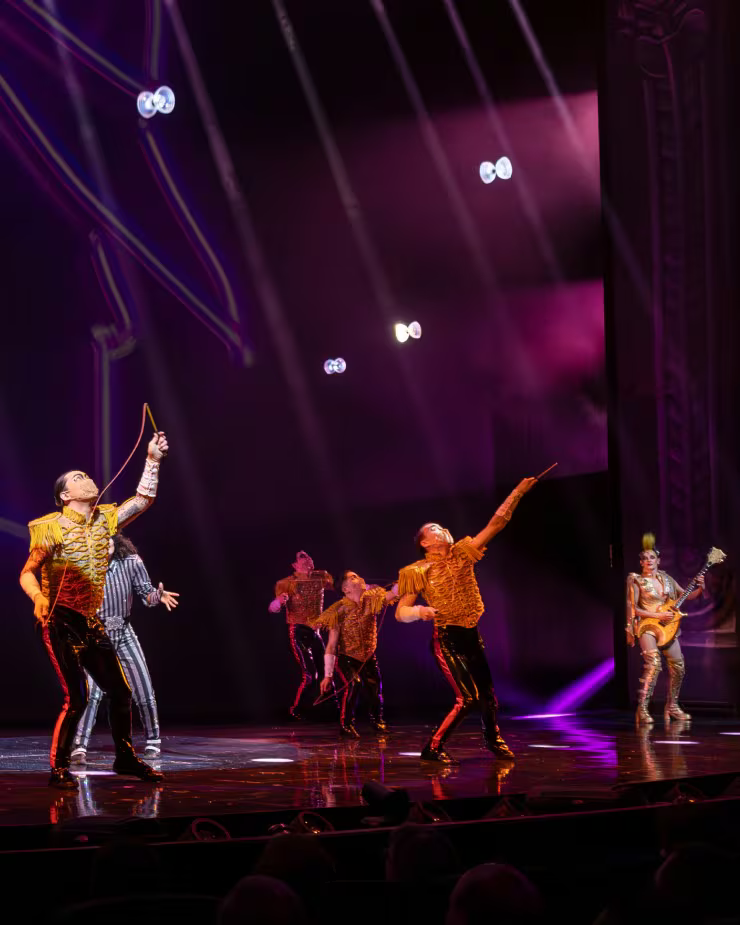 Dancers in bright costumes under purple stage light in Michael Jackson ONE