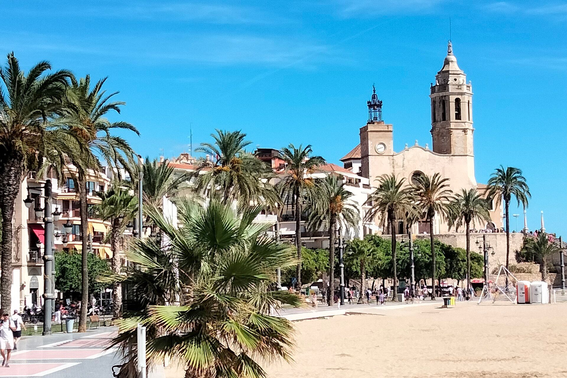 The church of Sant Bartomeu i Santa Tecla above the palm-lined promenade and sand of Platja de la Fragata in Sitges