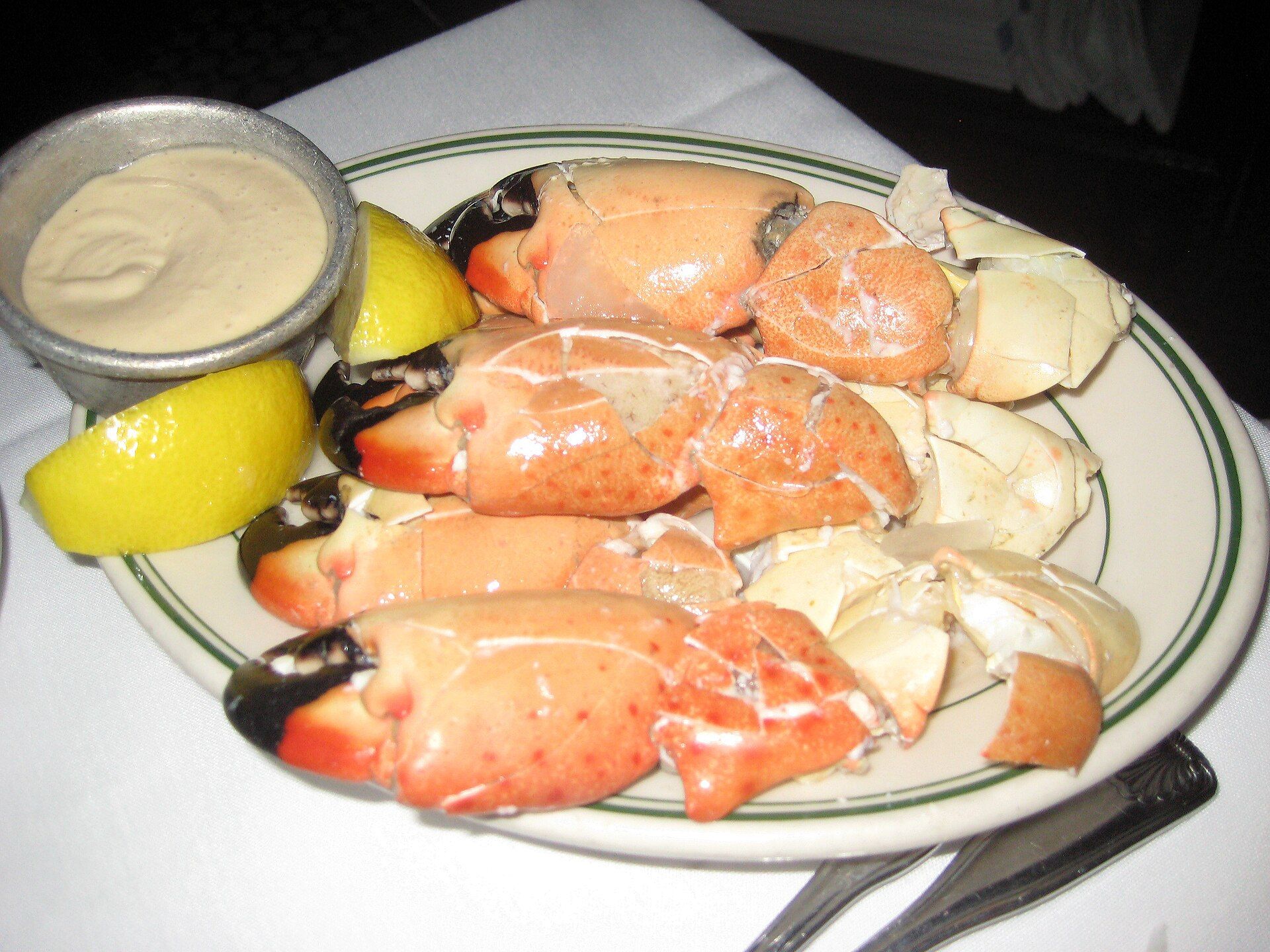 A plate of cracked stone crab claws with mustard sauce and lemon
