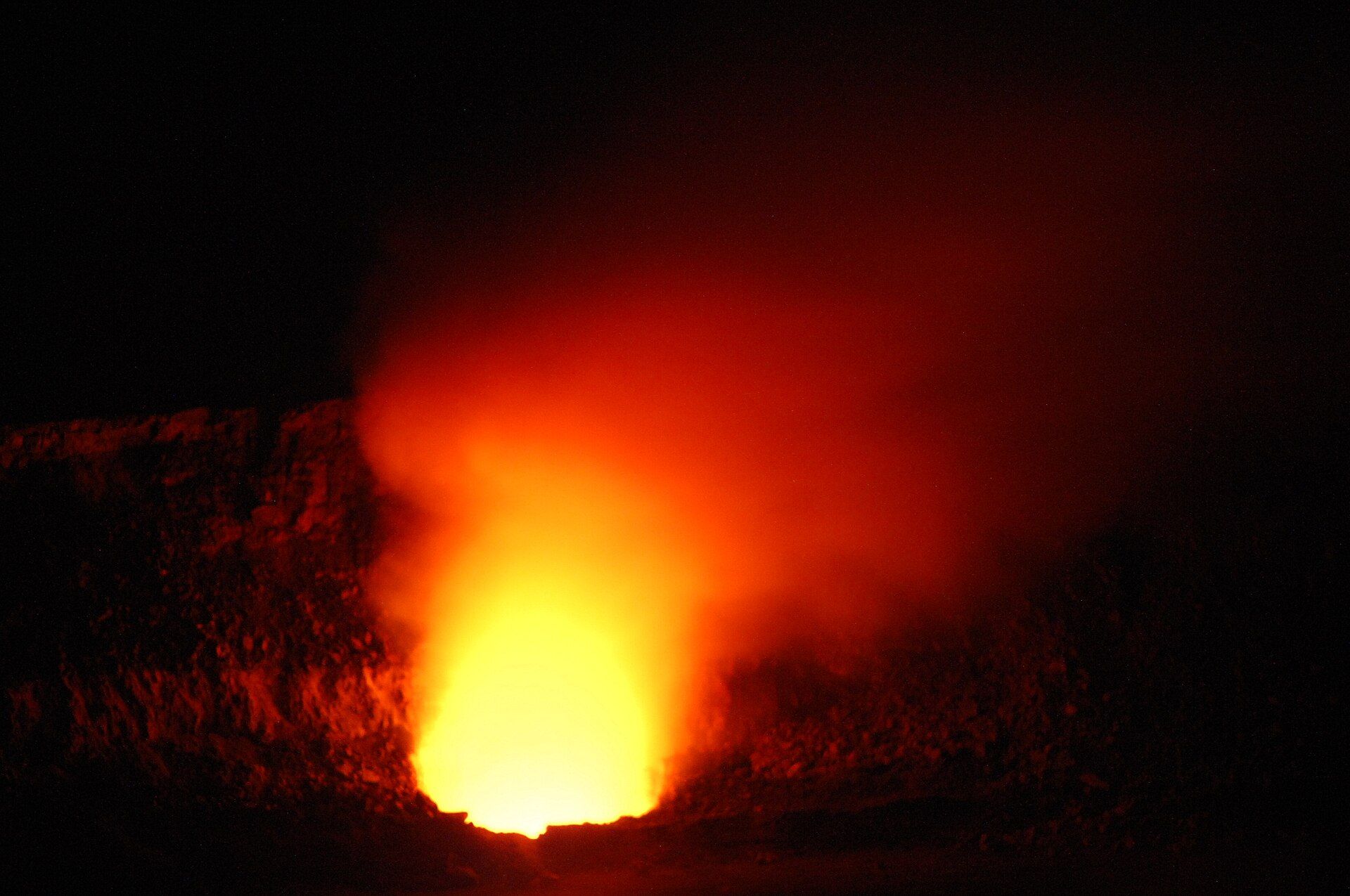 Orange lava glow rising from a crater at night