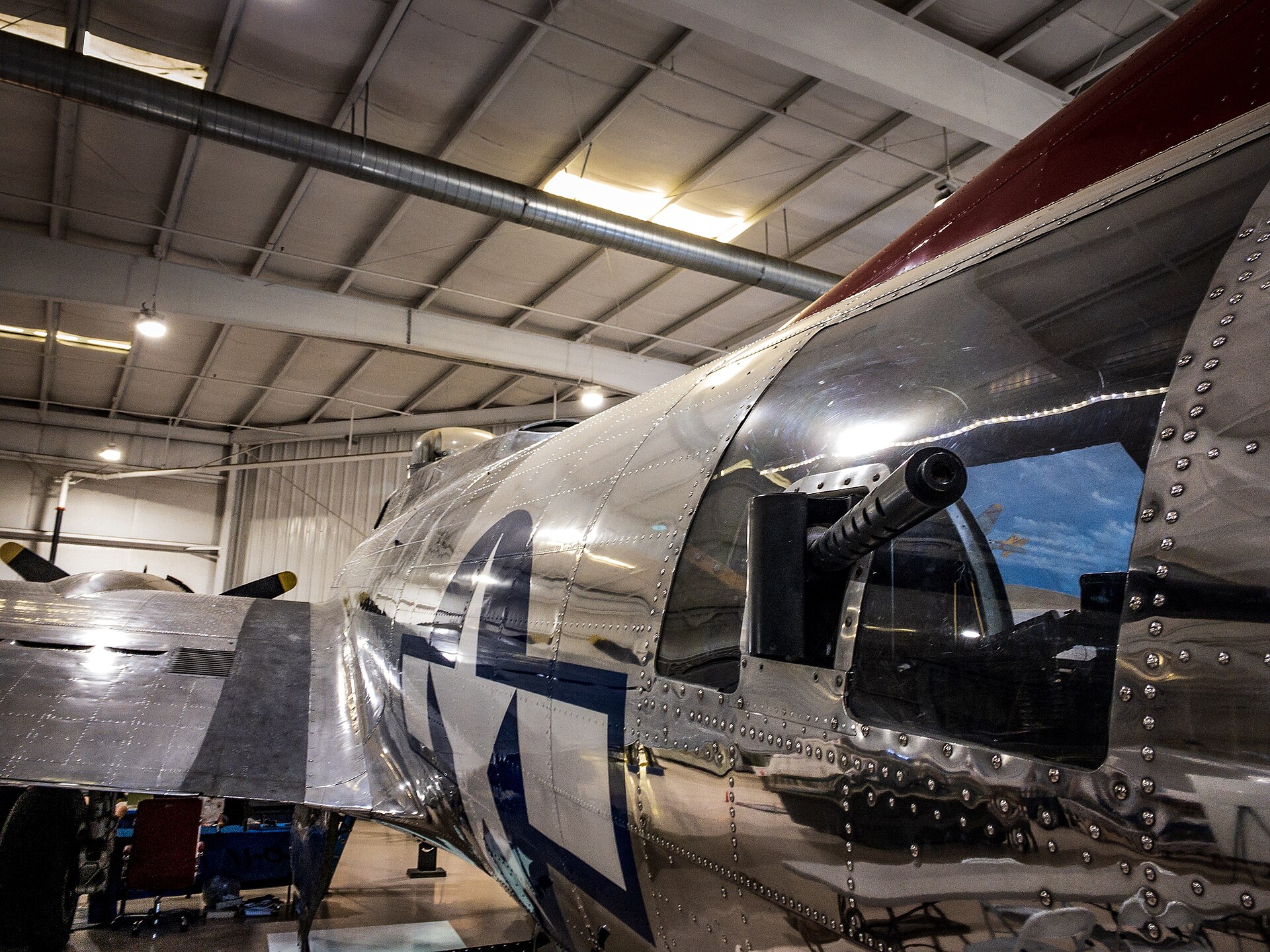 The polished aluminium nose and gun turret of a Second World War bomber inside a hangar