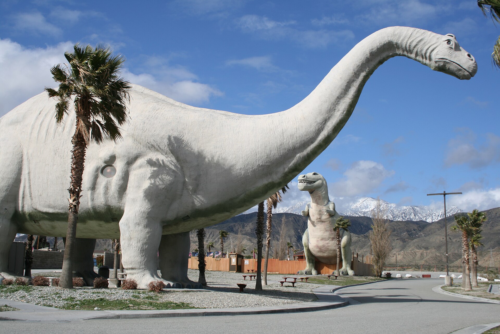 A huge green concrete brontosaurus standing beside a desert road