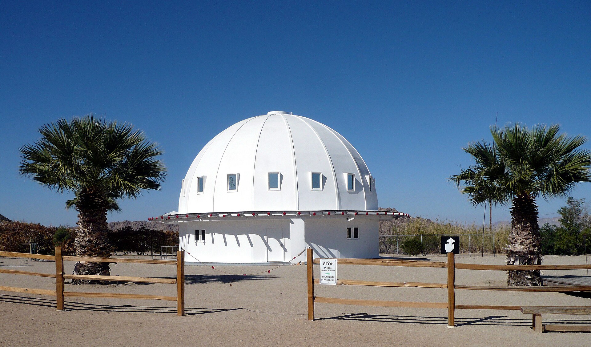 A white domed wooden building standing alone on flat open desert