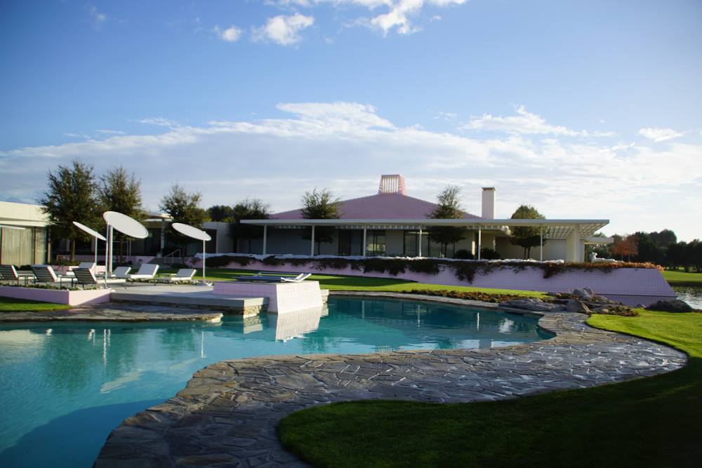 The low pink roof and glass walls of the Sunnylands house behind desert planting