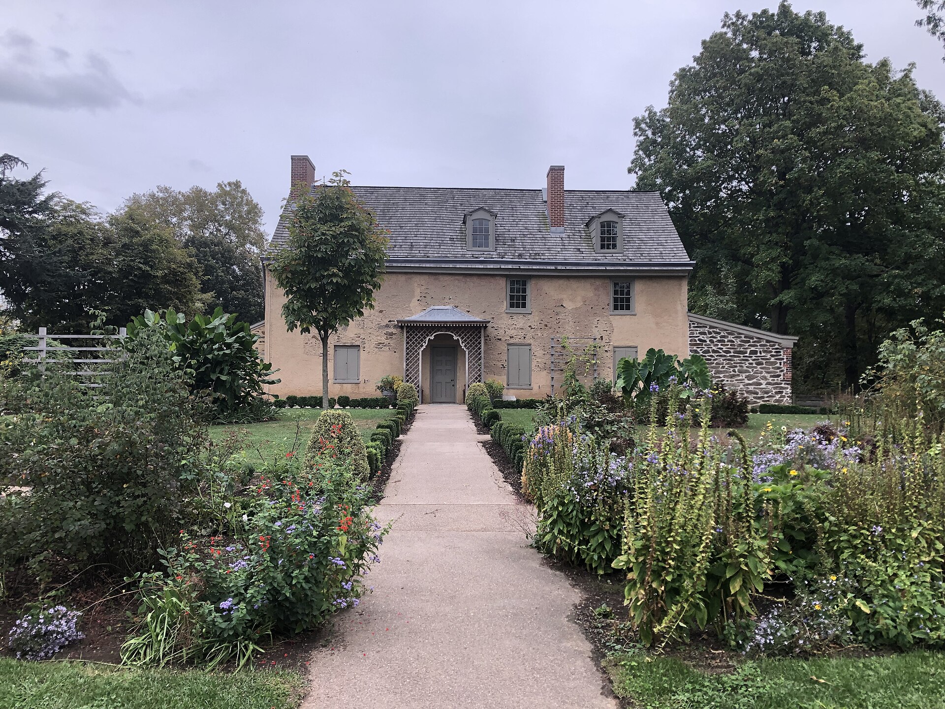 The stone front of John Bartram’s 18th century house behind a path lined with flower beds
