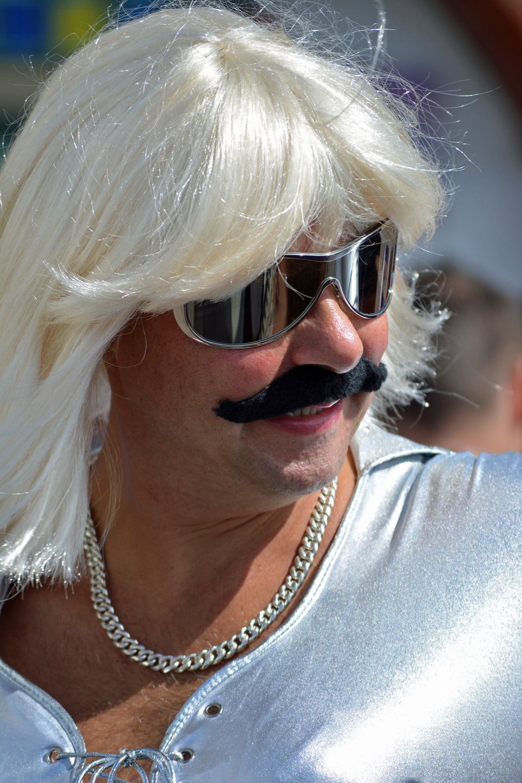 A performer in an elaborate costume and moustache at a pride parade